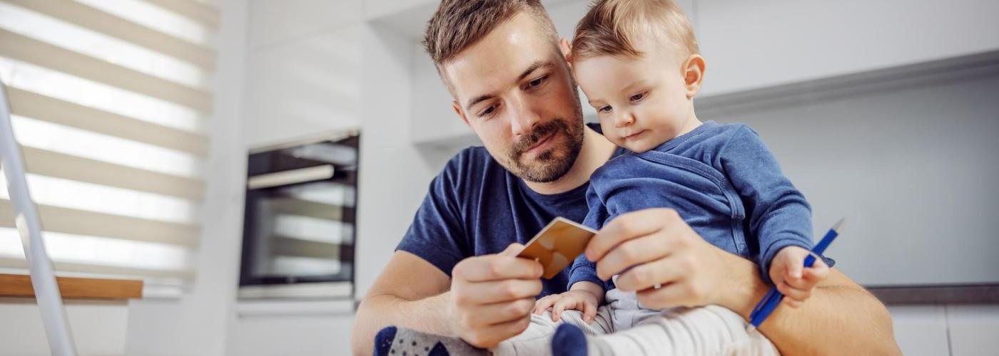 爸爸和宝宝看着信用卡在电脑上支付账单. 